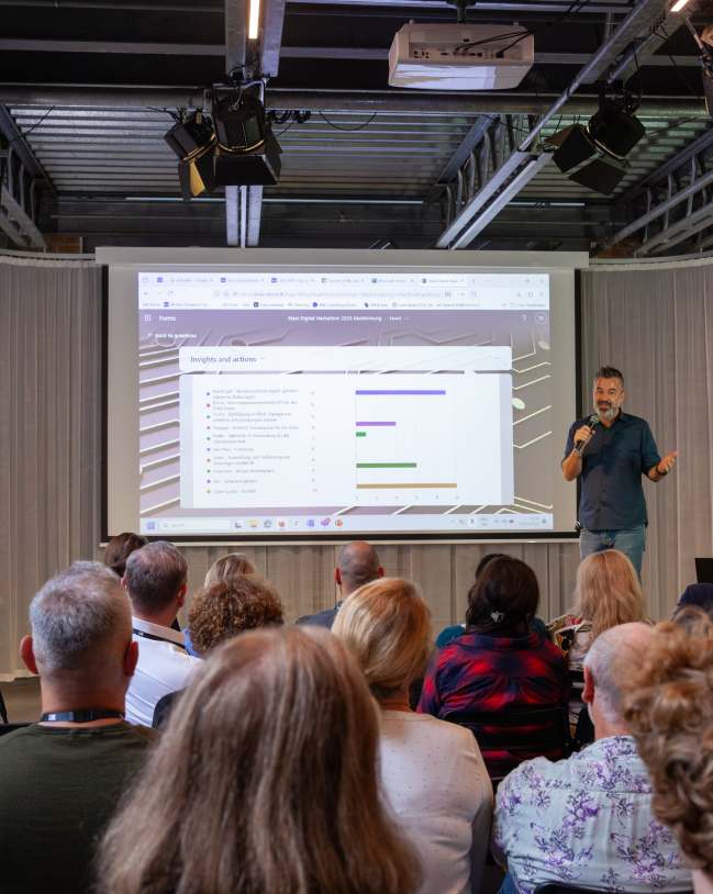 Dominik Multhaupt präsentiert seinen Vortrag vor einem Saal voller Menschen.