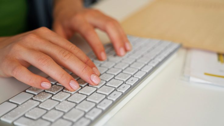 Eine Frau tippt auf einer Tastatur mit Braille-Schrift.
