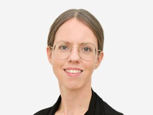 Eine Frau mit großer Brille lächelt in die Kamera.